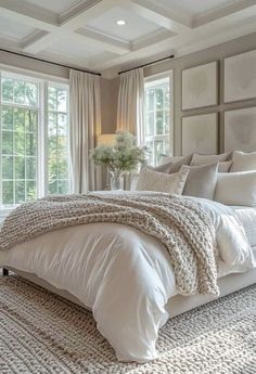 a large white bed sitting in a bedroom next to two windows and a rug on the floor