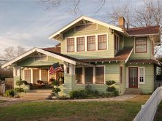 a green house with an american flag on the front porch