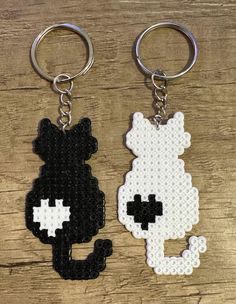 two keychains made out of legos on a wooden surface, one has a black and white cat