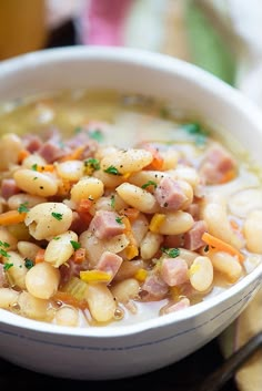 a close up of a bowl of soup with ham and beans in it on a table