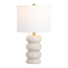 a white lamp with a gold base and a white linen shade on the top of it