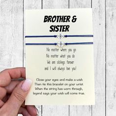 a hand holding up a card that says, brother and sister on the front with a blue string attached to it