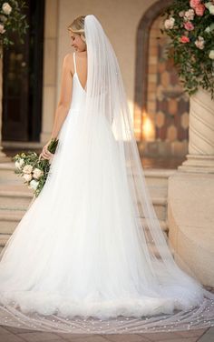 a woman in a white wedding dress standing on steps with her veil over her head