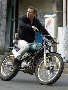 a man riding on the back of a motorcycle down a street next to a building