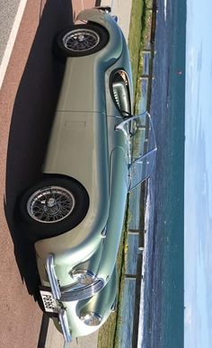 an old car parked next to the water