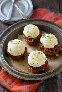 four mini meatloafs with cream cheese on top in a metal pan, ready to be eaten