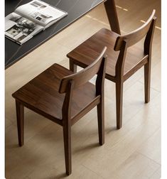 two wooden chairs sitting next to each other on top of a hard wood floored floor