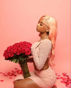 a woman sitting on the ground holding a bouquet of roses and looking up at it