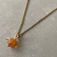 "NATURAL CARNELIAN AGATE CRYSTAL SATURN NECKLACE This necklace features a dainty, natural gemstone threaded on a 14k Gold Filled, Stainless Steel chain.  The pendant is completely handmade. Made with tarnish resistant gold plated wire. Available in color options, this necklace is ideal for layering & makes the perfect gift! Orange Carnelian gives courage and promotes positive life choices. A stabilising stone, Carnelian restores vitality and motivation, and stimulates creativity.  It gives courage, promotes positive life choices, dispels apathy and motivates for success.  ☆ Each of the stones we use to create necklaces were formed by nature over years. Each one is unique and beautiful just like nature itself.  We do not process or change our stones in any way, we accept their \"unique and Orange Crystal Necklace, Orange Necklaces, Orange Gifts, Saturn Pendant, Orange Accessories, Saturn Necklace, Creative Necklace, Orange Jewelry, Planet Necklace