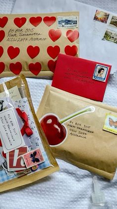 three envelopes with hearts on them sitting on a bed