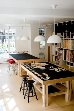 a room filled with lots of tables and chairs next to a book shelf full of books