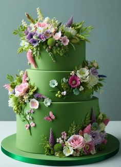 a three tiered green cake with flowers on it