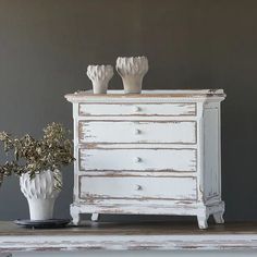 two white vases sitting on top of a wooden table next to an old dresser