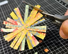 a person cutting up some paper with scissors on top of a piece of cloth that has been cut into small pieces