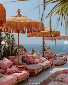 an outdoor lounge area with pink cushions and umbrellas