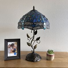 a lamp with a blue shade sitting on top of a table next to a potted plant