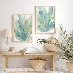 two paintings hang on the wall above a wooden table with wicker baskets underneath it