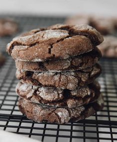 chocolate crinkle cookies stacked on top of each other, cooling on a wire rack