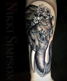 an elephant with flowers on it's head is shown in black and grey ink