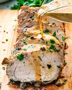 sliced pork roast with gravy being drizzled over it on a cutting board