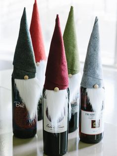 four wine bottles with gnome hats on them sitting on a table next to each other