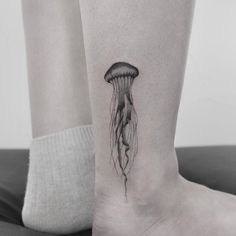 a black and white photo of a jellyfish tattoo on the ankle by an unknown person