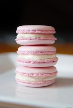 a stack of pink and white macaroons sitting on top of a white plate