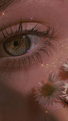 a close up of a person's eye with flowers in front of her face