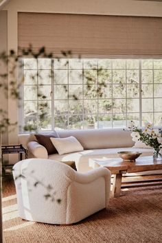 a living room filled with white furniture and lots of window sill space next to a coffee table