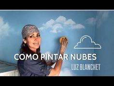 a woman holding up a doughnut in front of a blue wall with clouds and the words como pintar nubes