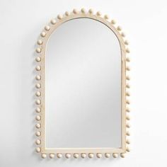 an oval mirror with beaded edges and a wooden frame, hanging on the wall