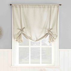 a kitchen window with a checkered valance and bow tie - up curtains hanging on the side