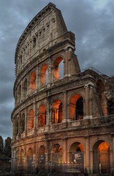 the roman colossion lit up at night with its lights on and dark clouds in the background