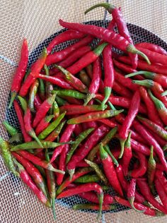 there are many red and green peppers in the bowl on the table, ready to be eaten