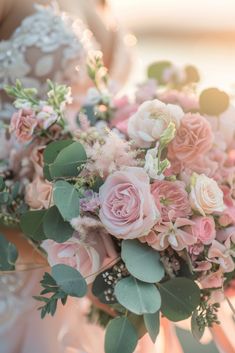 a bridal holding a bouquet of pink flowers and greenery in her hands,