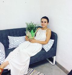 a woman sitting on a couch holding a potted plant