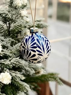 a blue and white ornament hanging from a christmas tree