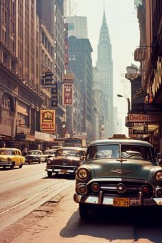 an old green car driving down a street next to tall buildings in new york city