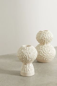 two small white vases sitting on top of a table next to each other,