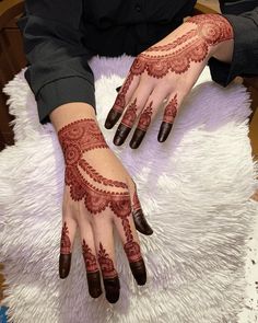 a woman's hands with hennap painted on them sitting on a white rug