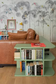 a living room with a couch, bookshelf and wallpaper