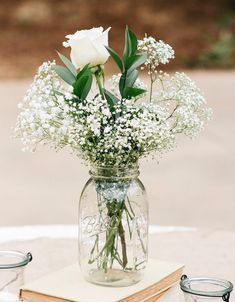 a vase filled with white flowers sitting on top of a table next to two candles