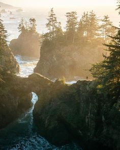 the sun shines through the trees and over the water at an island with many rocks