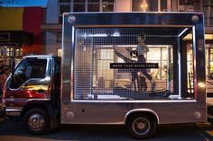 a silver truck is parked in front of a building with people walking around it at night