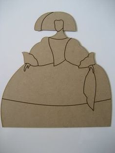 a paper cutout of a woman with a hat and scarf on her head, sitting in front of a white wall