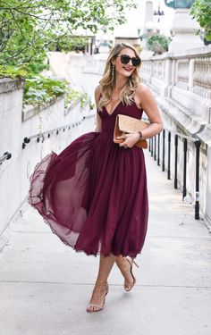 a woman in a purple dress is walking down the street with her hand on her purse