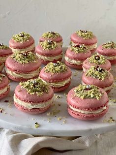 there are many pink and white macaroons on the plate with sprinkles