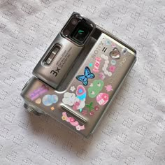 a cell phone sitting on top of a white tablecloth covered surface with stickers