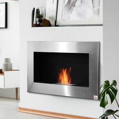 a modern fireplace in a living room with pictures on the wall and a potted plant next to it