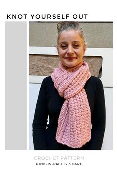 a woman wearing a pink knitted scarf and black shirt standing in front of a white wall